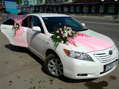 Bright vehicle decor with soft pink fabric and bouquet of pink and white flowers.