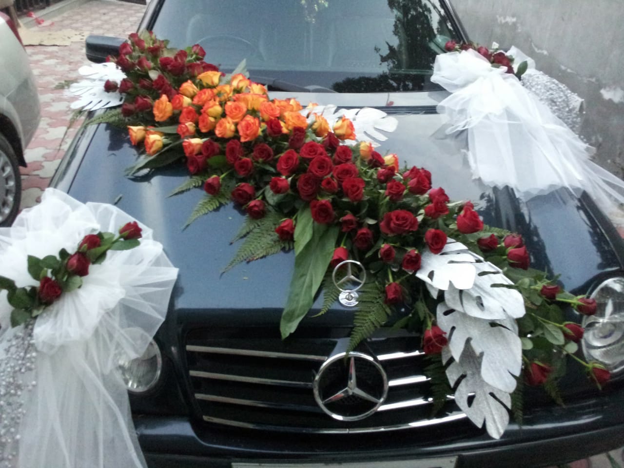 Long bouquet decor for vehicle decor with red and orange roses and white fabric